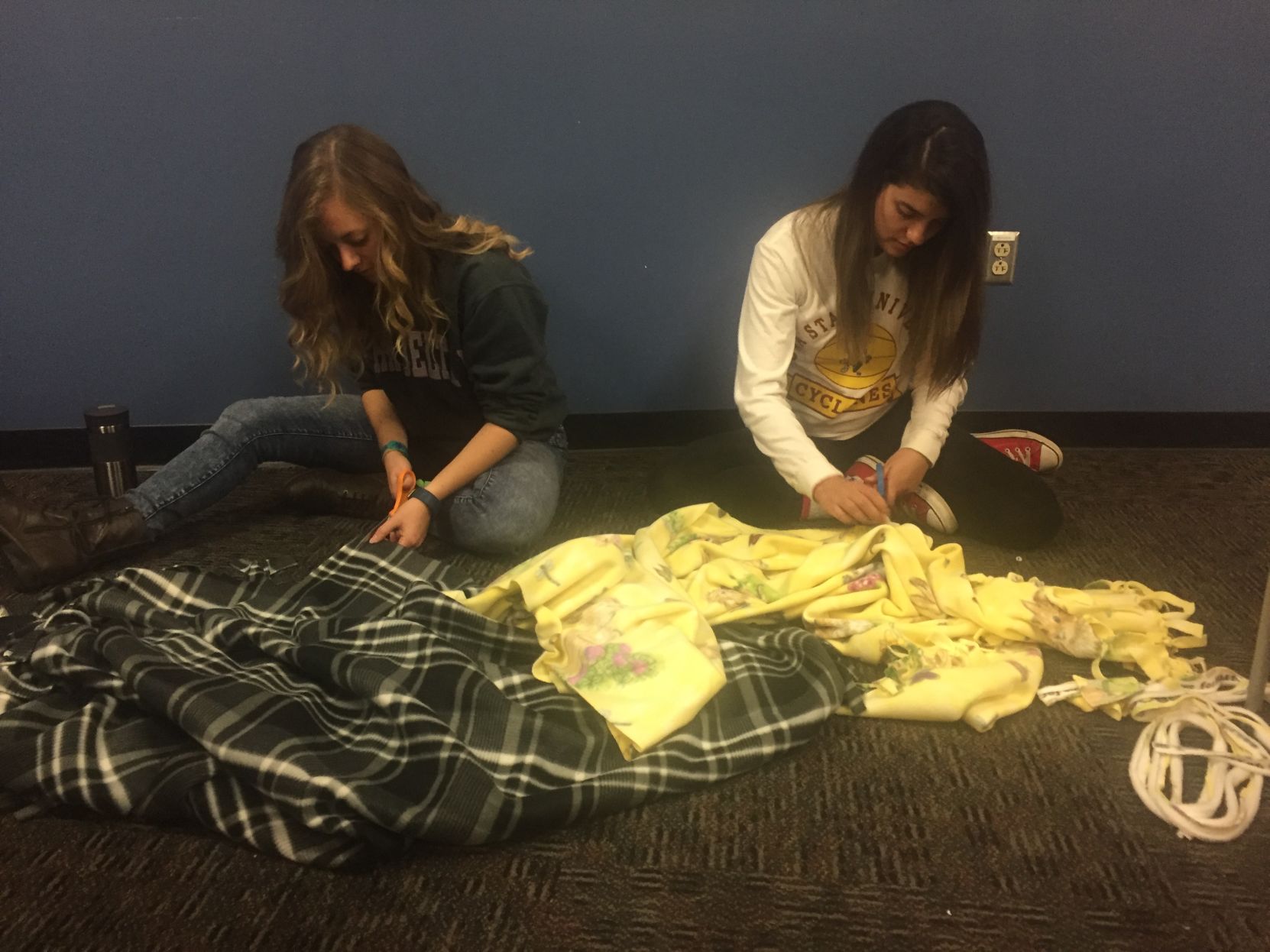 Two students sewing on a cloth.