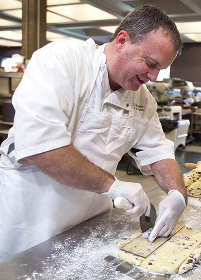 Image of baker hand cutting dough for made from scratch bakery items. 