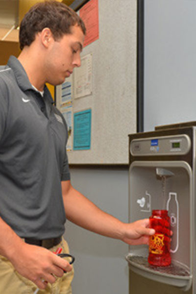 Student fills water bottle from a water re-fill station. 
