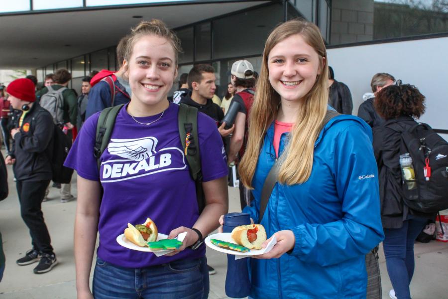 Two students with plates of food enjoy the celebration event. 