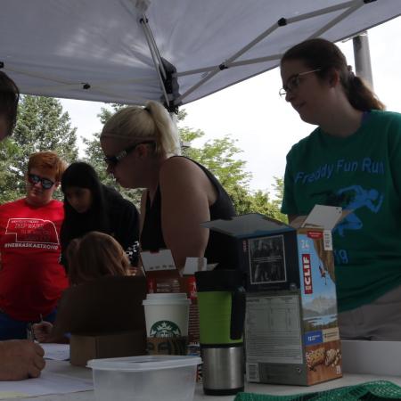 Volunteers organize tables of supplies during College Creek event. 